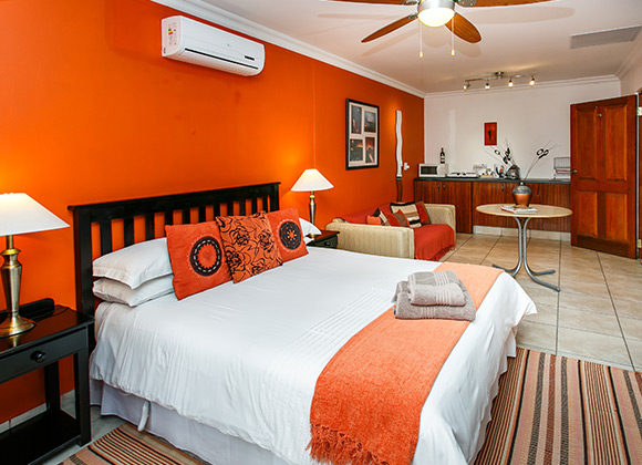 Bright bedroom with orange walls, large bed, and modern decor.
