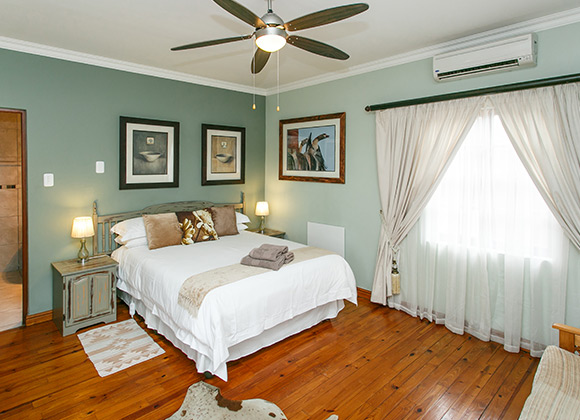 Bedroom with a large bed, wooden floor, and ceiling fan.