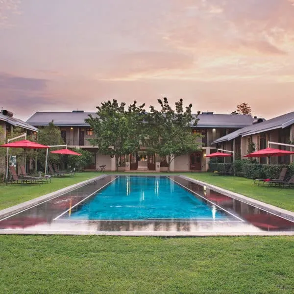 Swimming pool with lounge chairs and umbrellas in front of a building at sunset