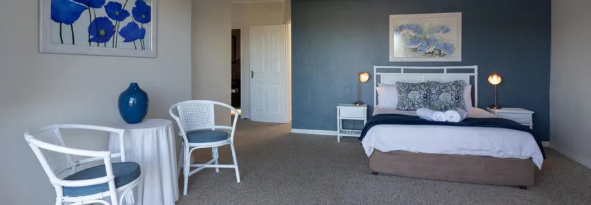 Bedroom with a bed side tables lamps chairs and a blue vase