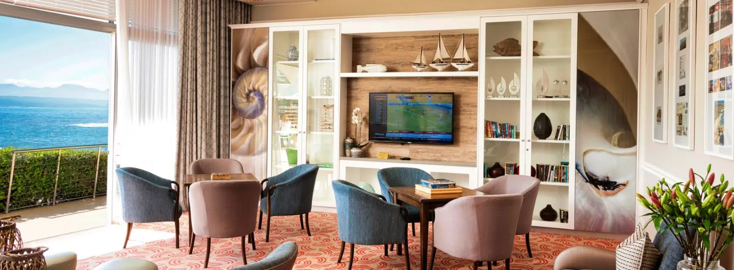 Cozy lounge with armchairs TV and sea view through large windows