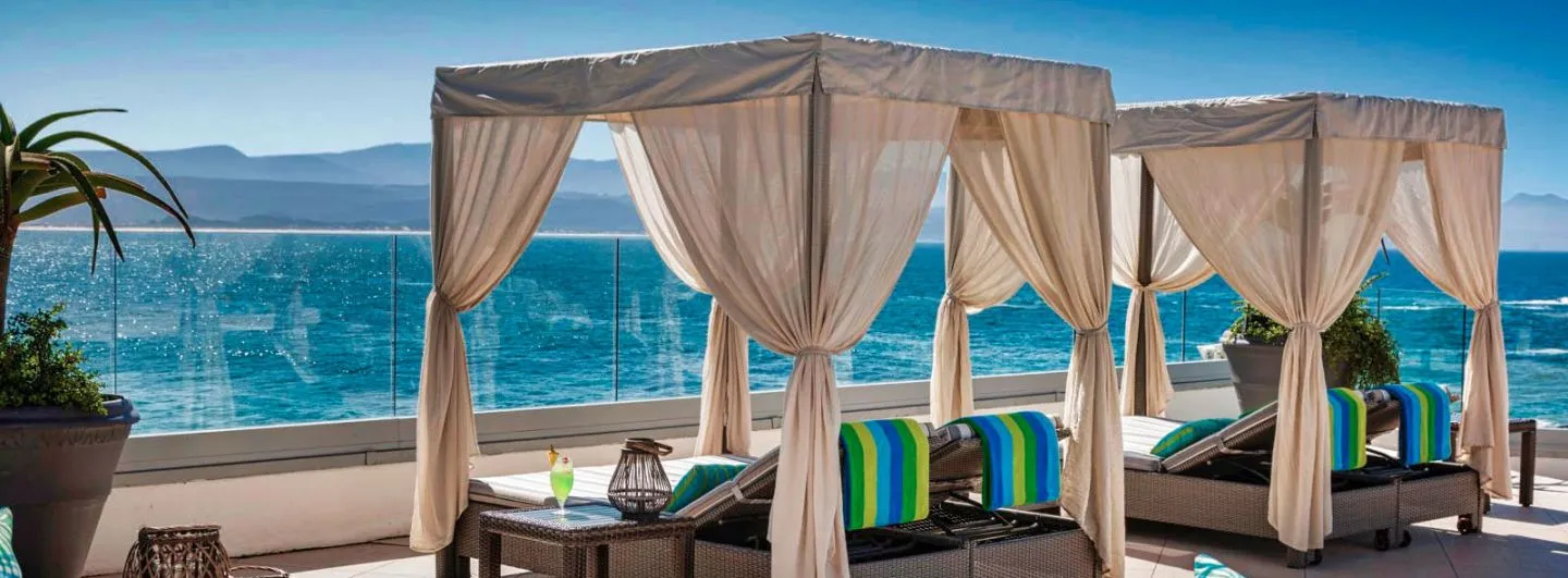 Two lounge chairs with canopies overlooking the ocean on a sunny day