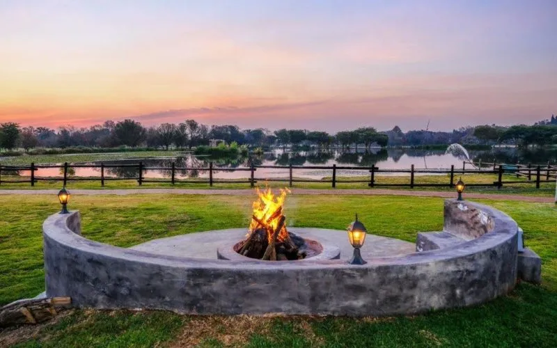 Outdoor fire pit with seating on a grassy field at sunset