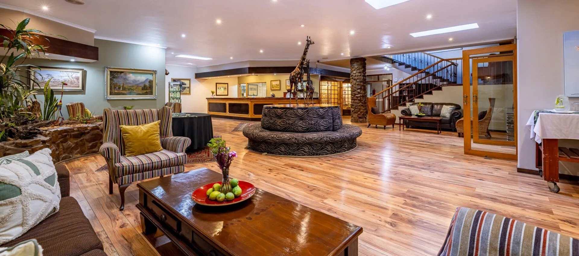 Cozy hotel lobby with wooden furniture fireplace and staircase leading to upper level