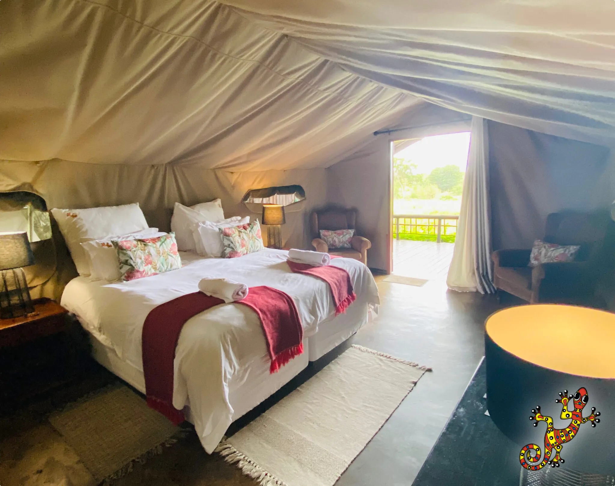 Cozy tent bedroom with two beds red throws and an open door to outside
