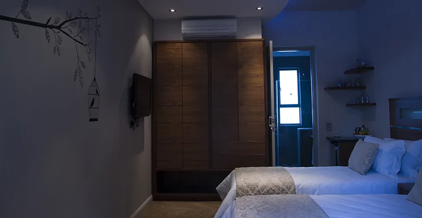 Modern bedroom with two beds wooden wardrobe and wallmounted TV