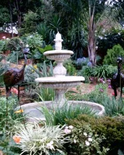 Ornate stone fountain in a lush garden with bird sculptures
