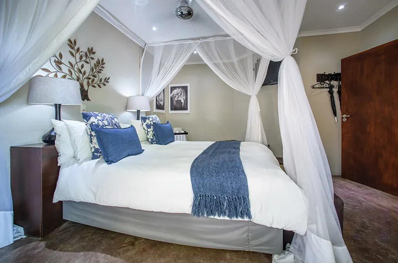 Large bed with blue and white bedding in a room with draped curtains