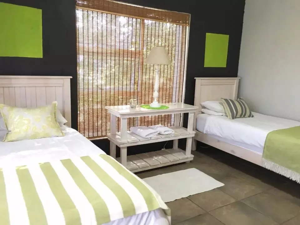 Two single beds in a bedroom with green and white decor and a window