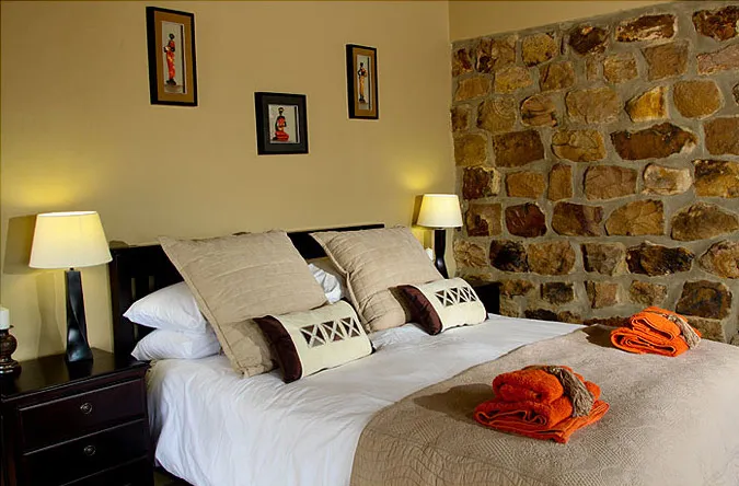Cozy bedroom with stone wall two beds and bedside lamps