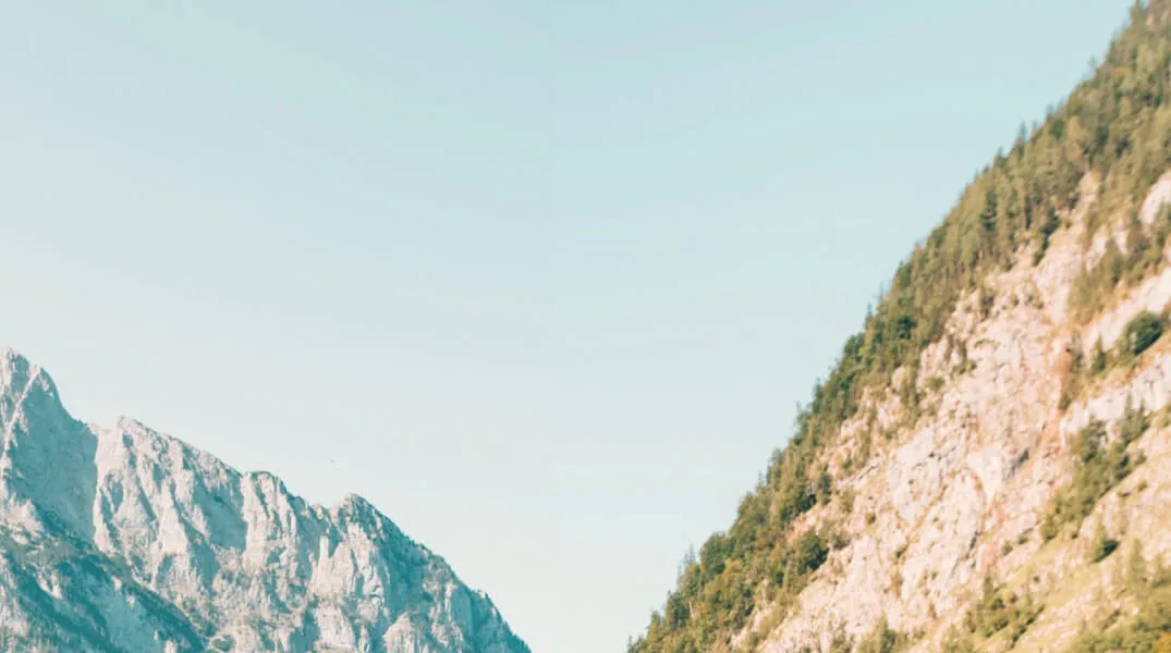 Mountain landscape with rocky slopes and greenery under a clear sky