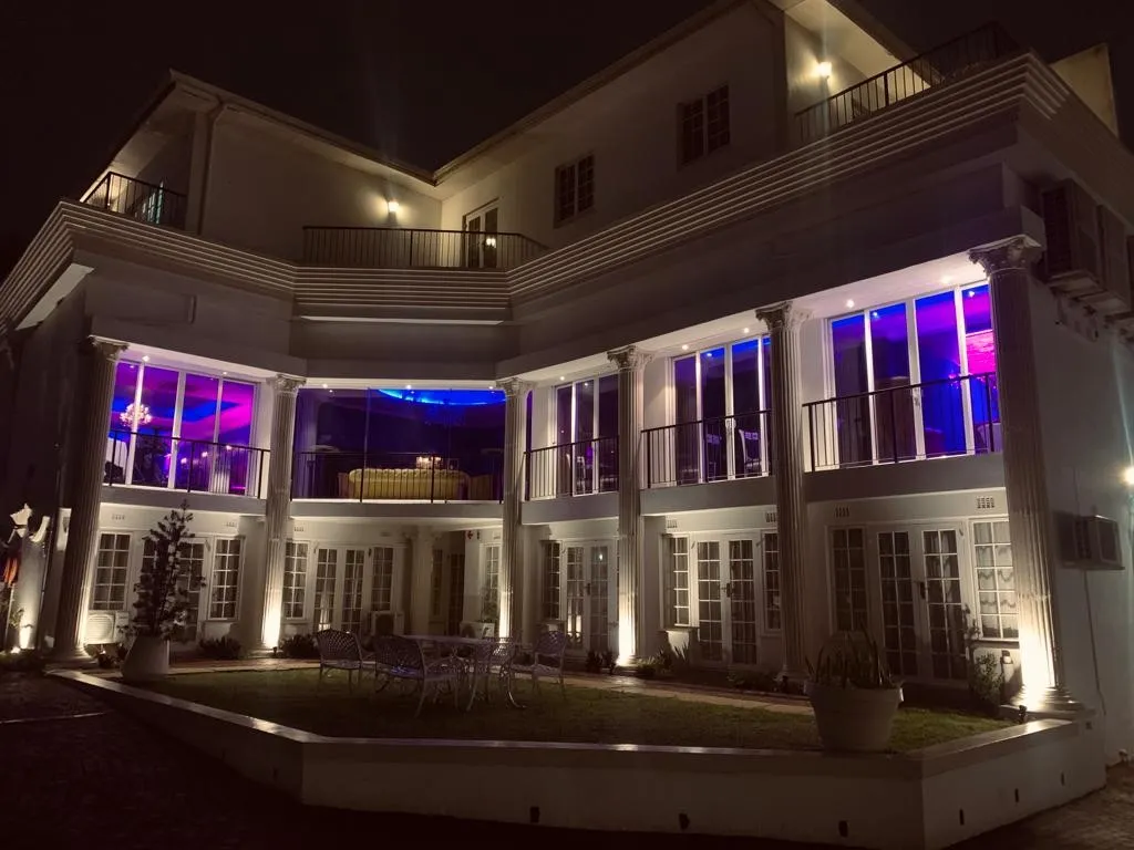 Modern house at night with purple and blue interior lighting and outdoor seating
