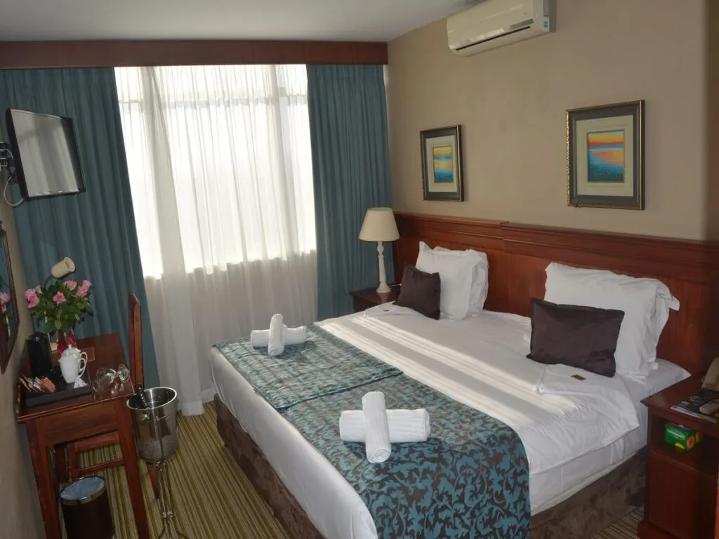 Hotel room with two beds desk lamp and wall art