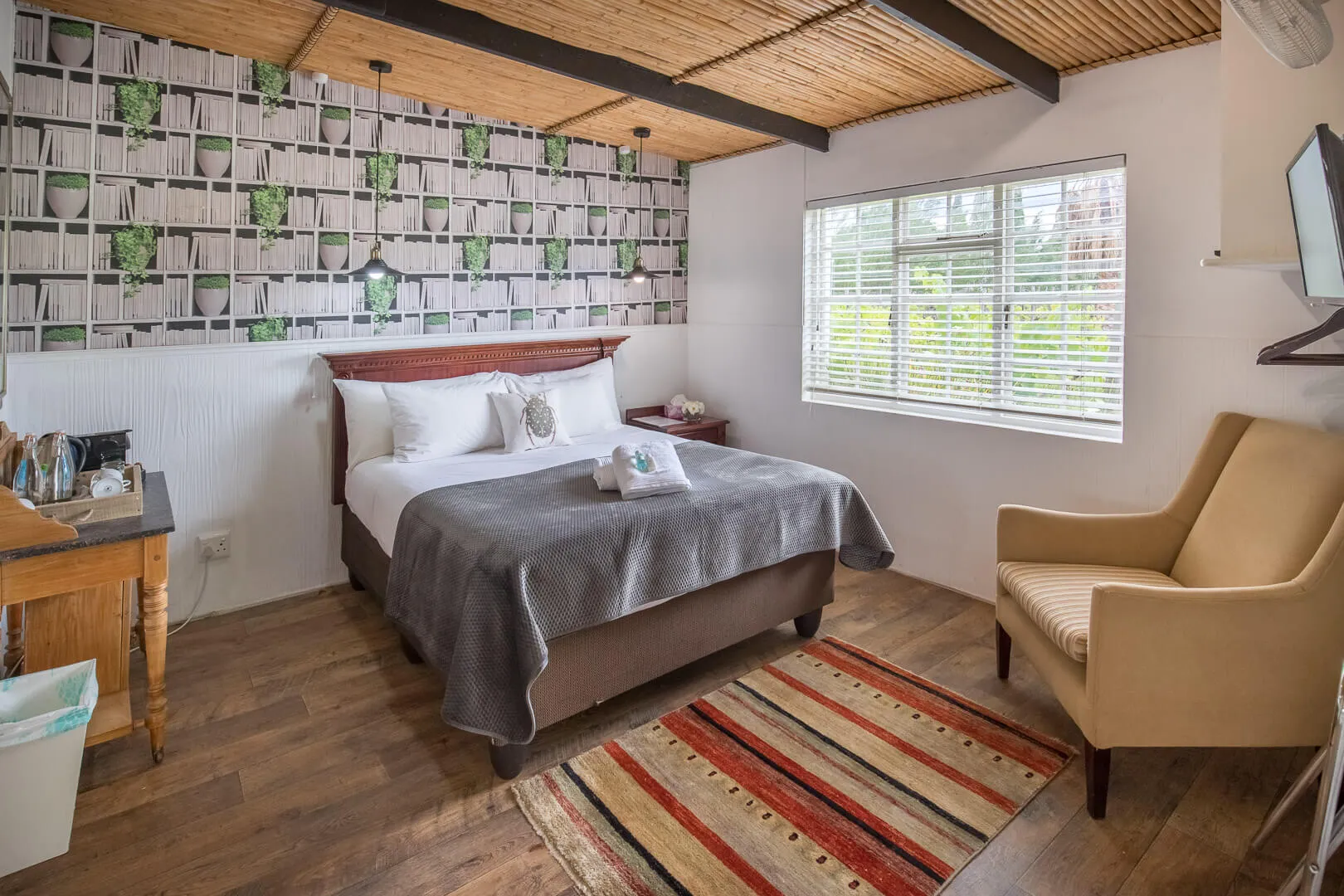 Cozy bedroom with a bed armchair wooden floor and patterned wallpaper