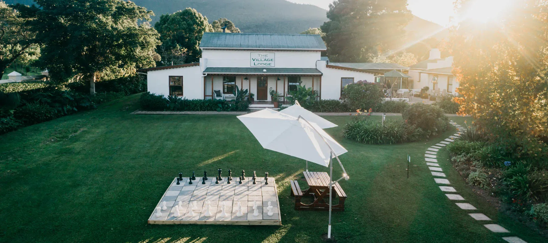 Large outdoor chess set in a garden with a house in the background
