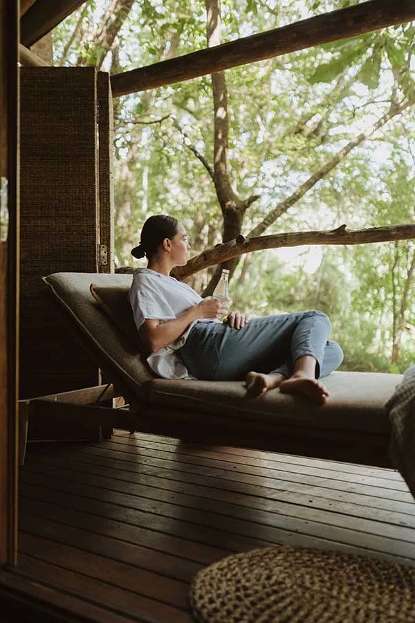 Woman relaxing on a lounge chair on a wooden deck surrounded by trees