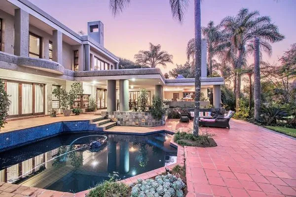 Modern house with pool palm trees and outdoor seating area at sunset