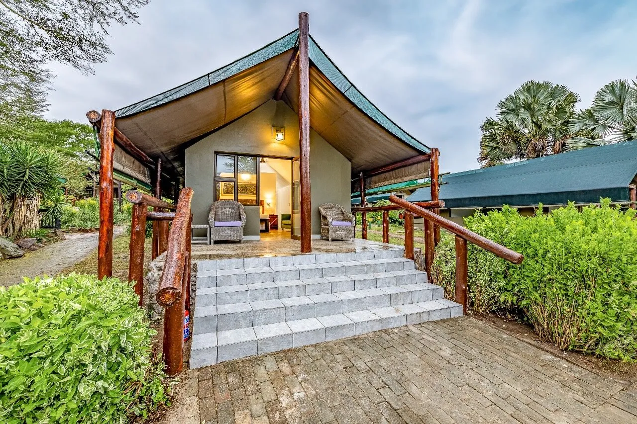 Wooden cabin with a porch surrounded by greenery and a paved pathway