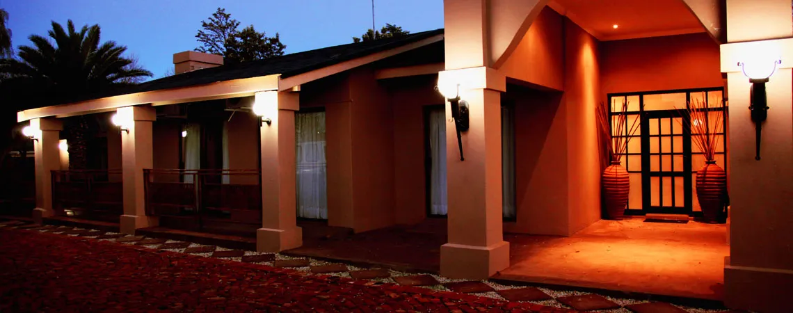 Evening view of a warmly lit building entrance with palm trees