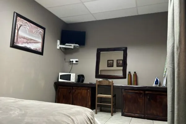 Cozy bedroom with bed desk chair microwave TV and wall art