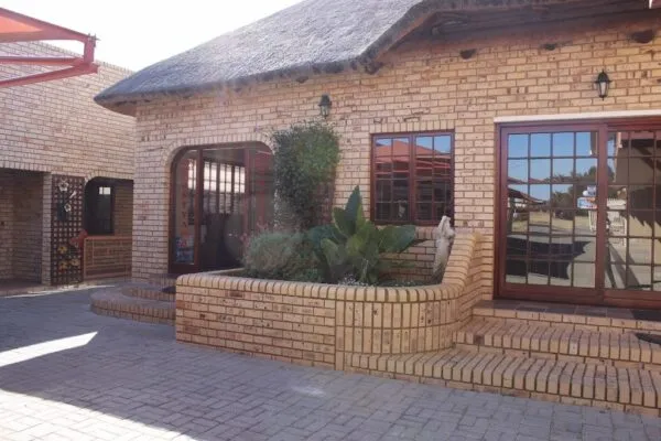 Brick house with large windows plants and paved walkway in sunlight
