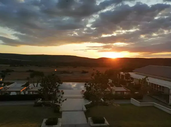 Sunset over a resort with a pool trees and buildings in the foreground