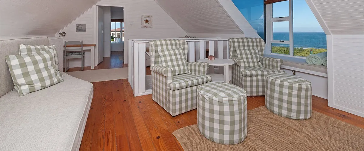 Cozy attic room with armchairs ottomans and a view of the ocean