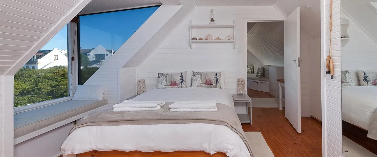 Bedroom with large bed white decor and slanted ceiling with a window