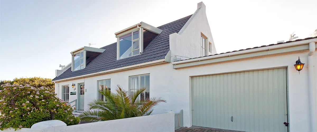 White house with grey roof dormer windows and attached garage in daylight