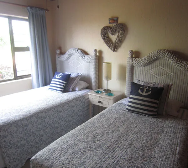 Two twin beds with nauticalthemed pillows in a cozy bedroom