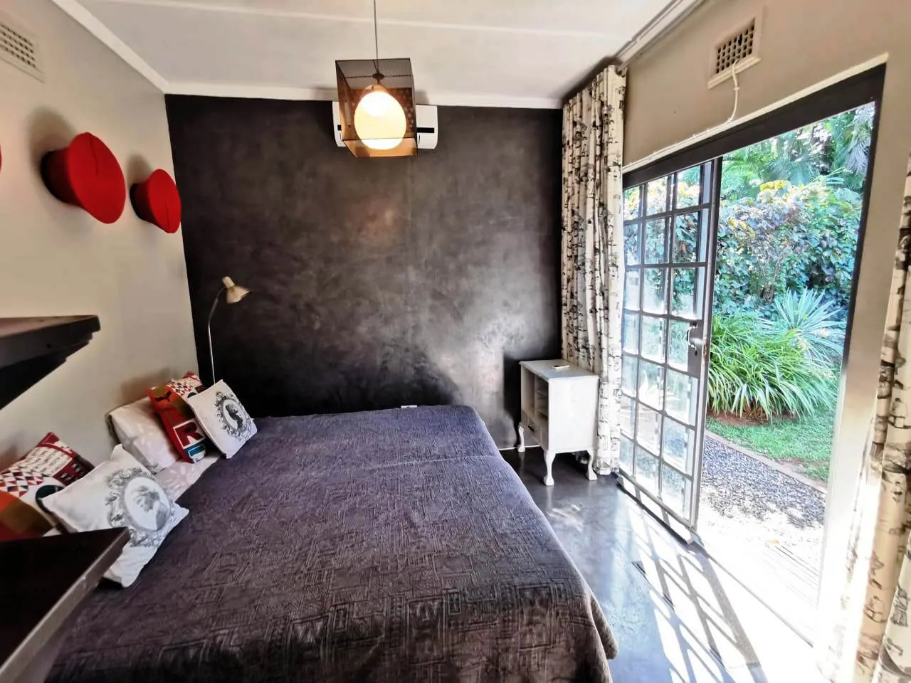 Bedroom with gray walls large bed and sliding glass door to garden