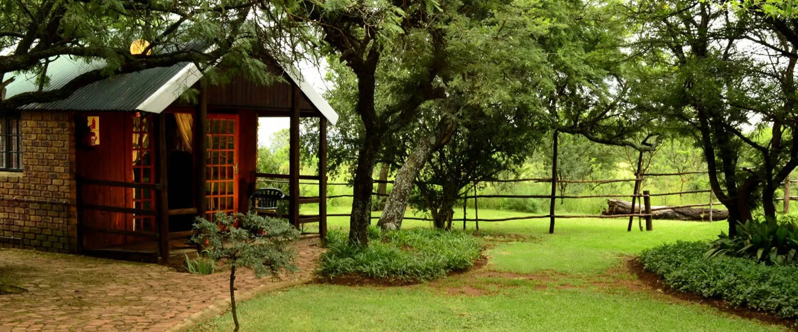 Wooden cabin in a lush green garden with trees and a pathway