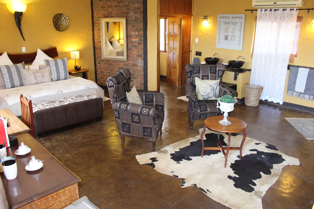 Cozy bedroom with armchairs cowhide rug and wooden furniture on brown floor