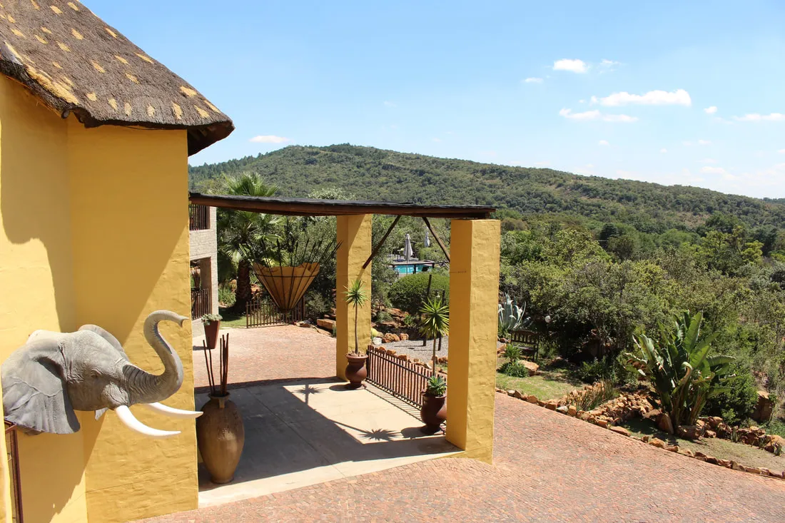 Yellow building with elephant sculpture overlooking a hilly landscape with trees
