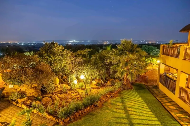 Evening view of a garden with plants and a building with lit balconies
