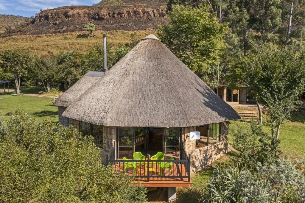 Thatchedroof hut with wooden deck in a lush green landscape