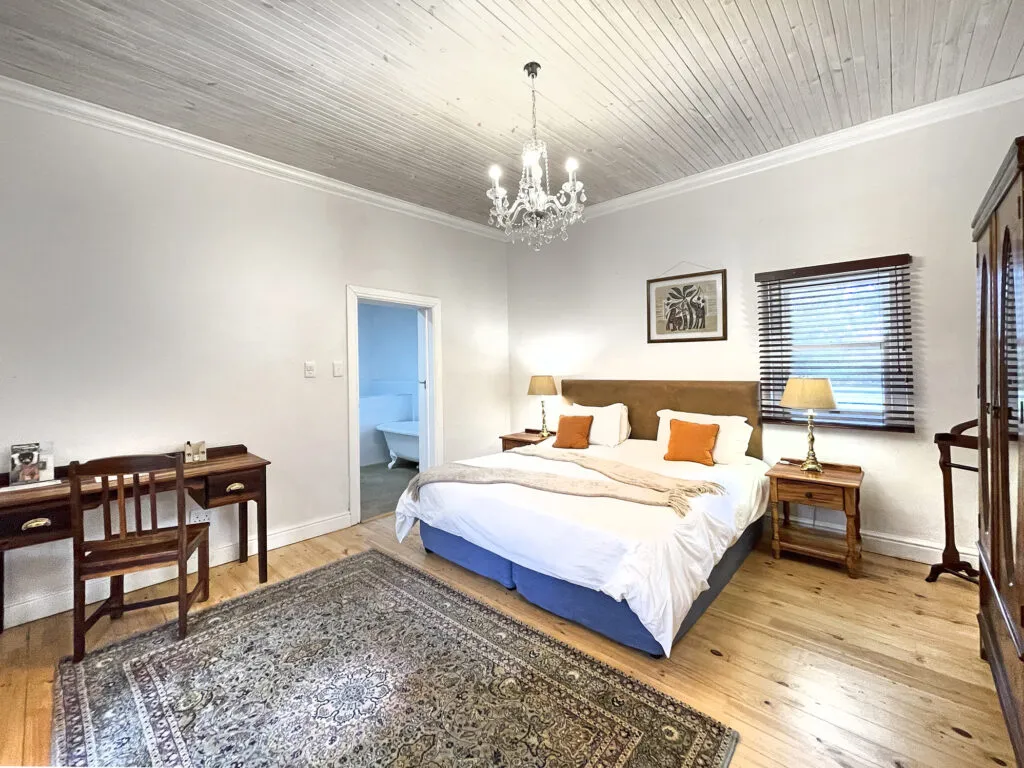 Bedroom with large bed wooden desk and chandelier featuring wooden floors and ceiling