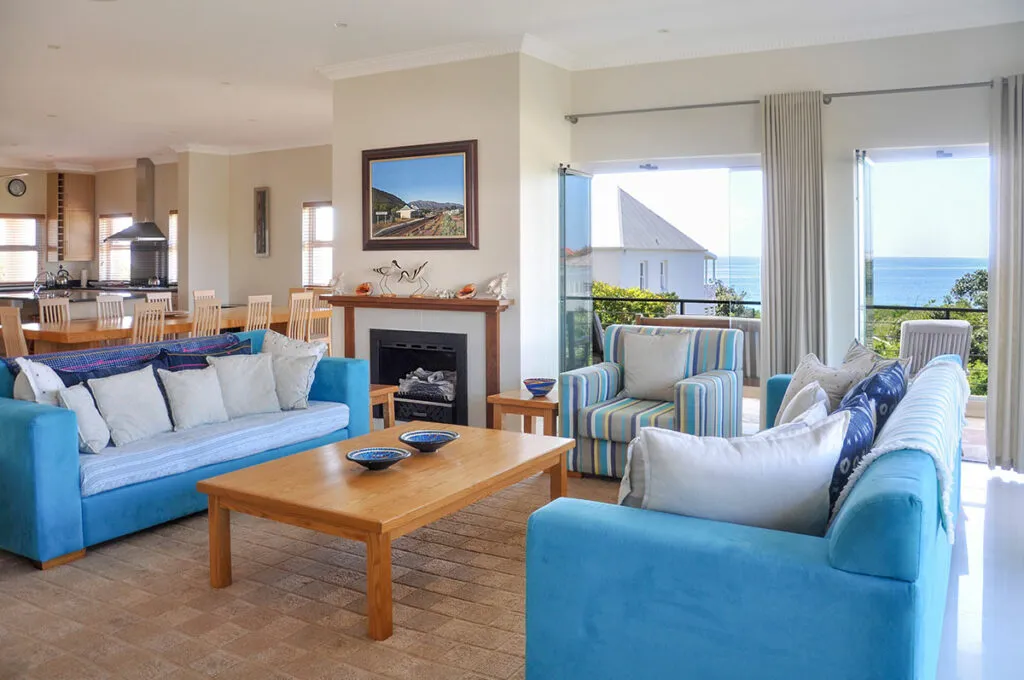 Living room with blue sofas wooden table and ocean view through large windows