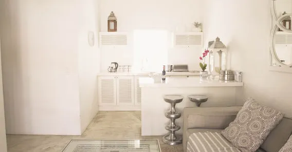 Bright kitchenette with sofa patterned cushions and stools in a cozy room
