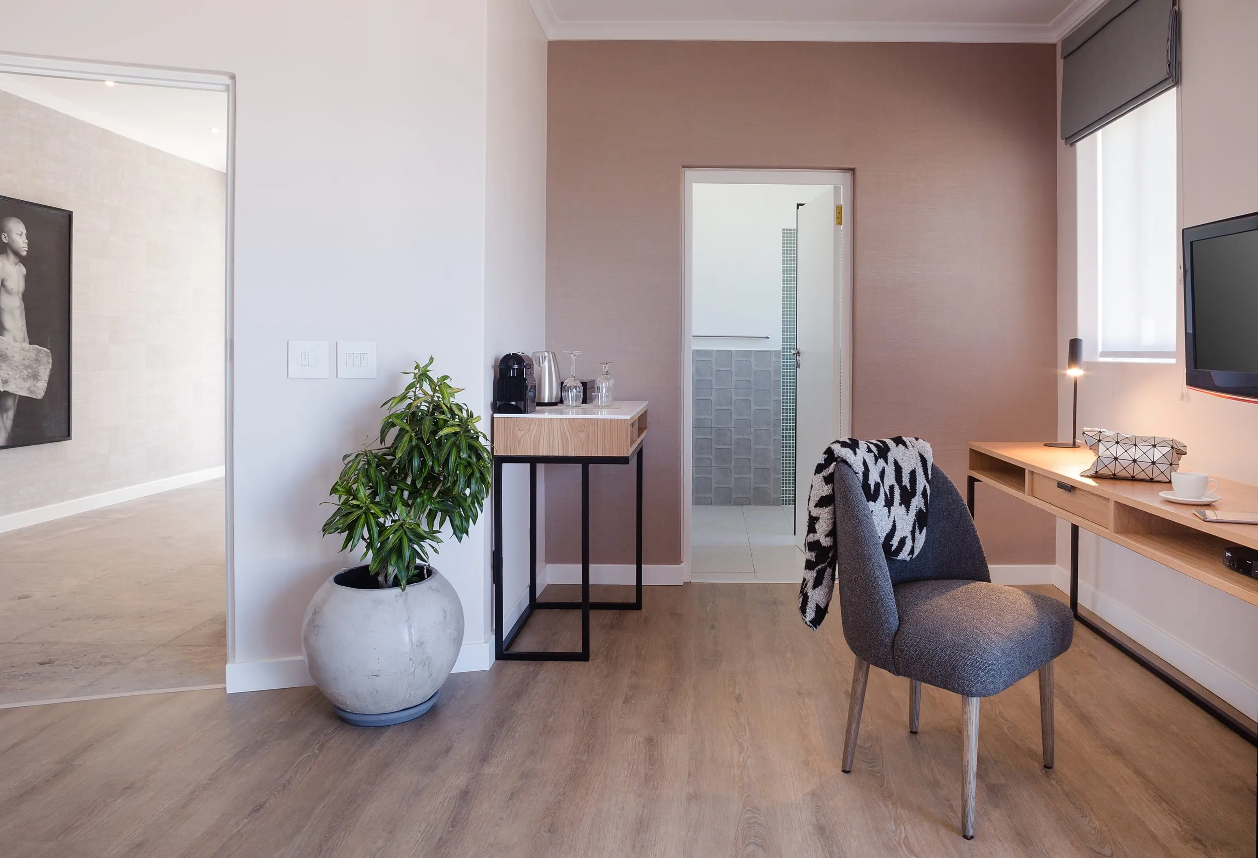 Modern hotel room with armchair desk and potted plant on wooden floor