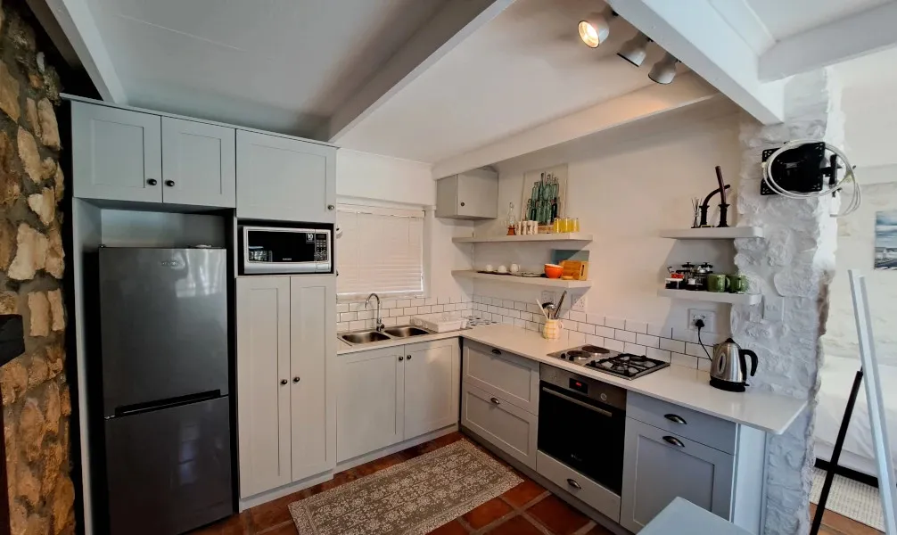 Modern kitchen with white cabinets stainless steel appliances and stone wall