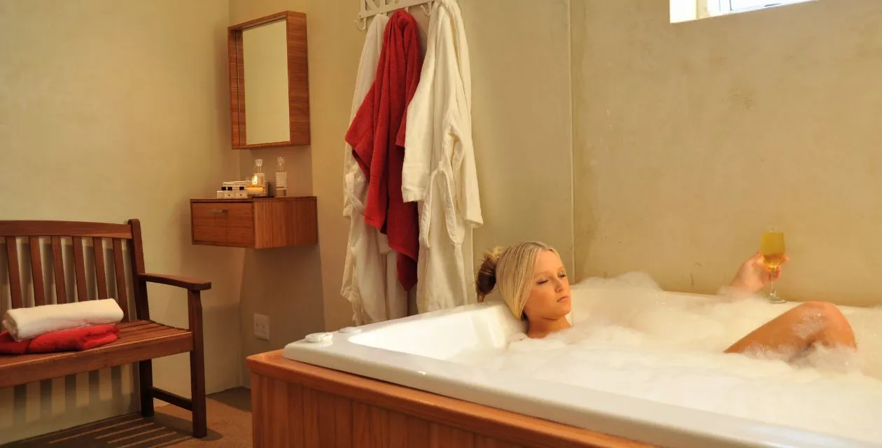Woman relaxing in a bubble bath holding a glass of wine in a cozy bathroom