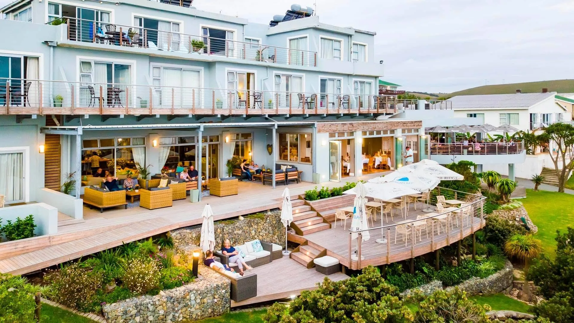 Coastal hotel with outdoor seating areas and lush greenery