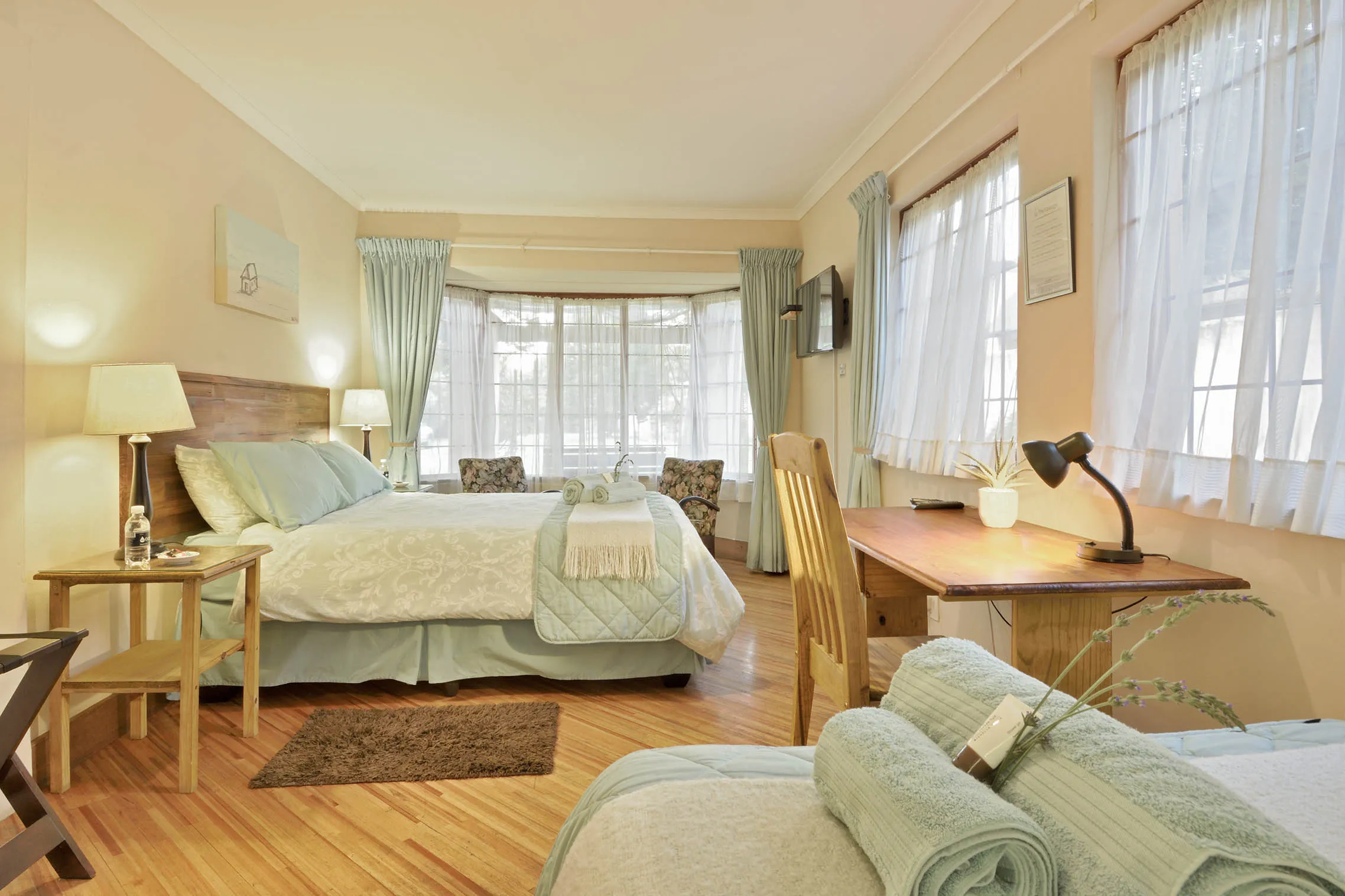 Bright bedroom with two beds large windows and wooden furniture