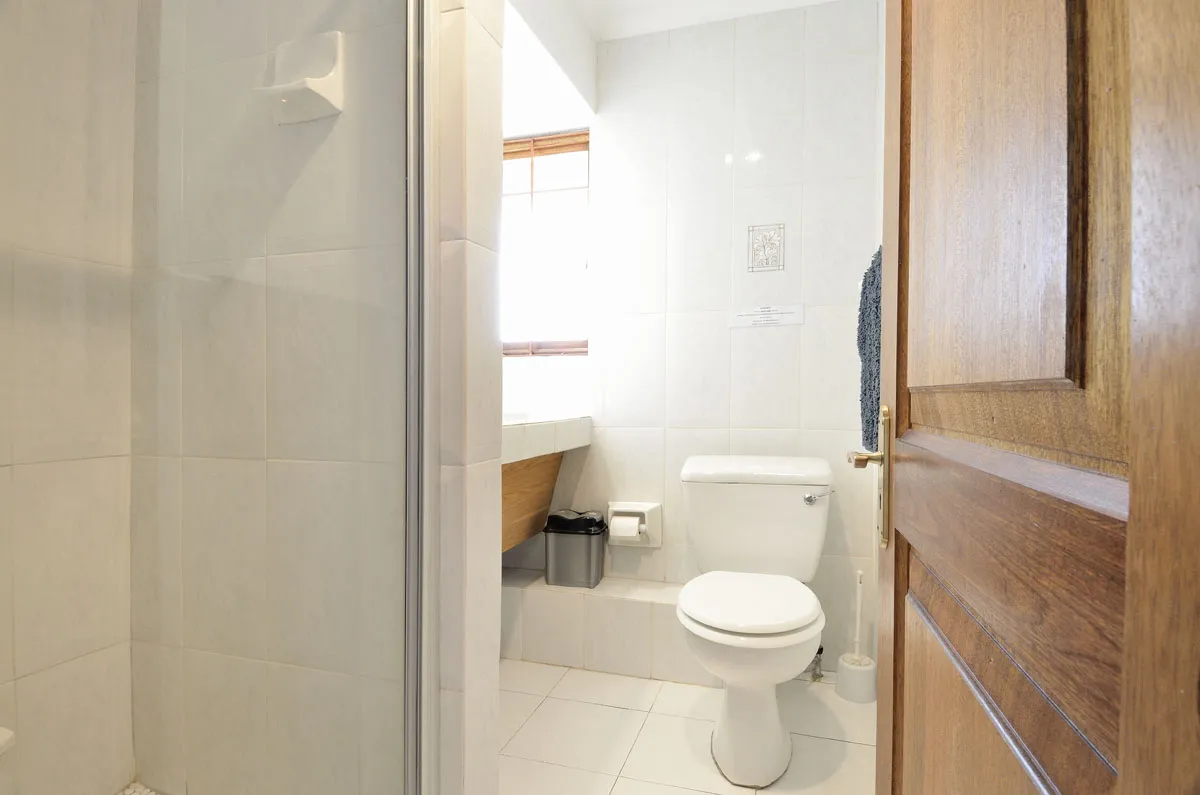 White bathroom with toilet sink and window viewed from an open door