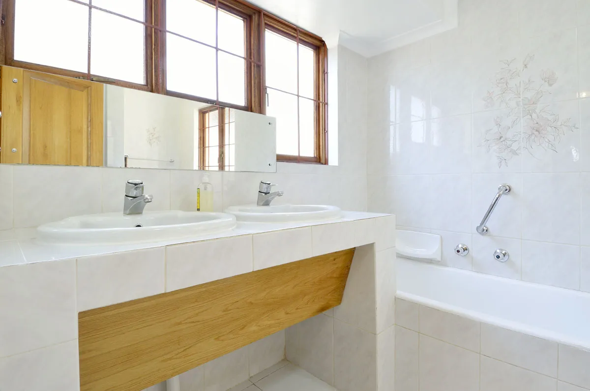 Modern bathroom with double sink mirror and bathtub featuring large windows