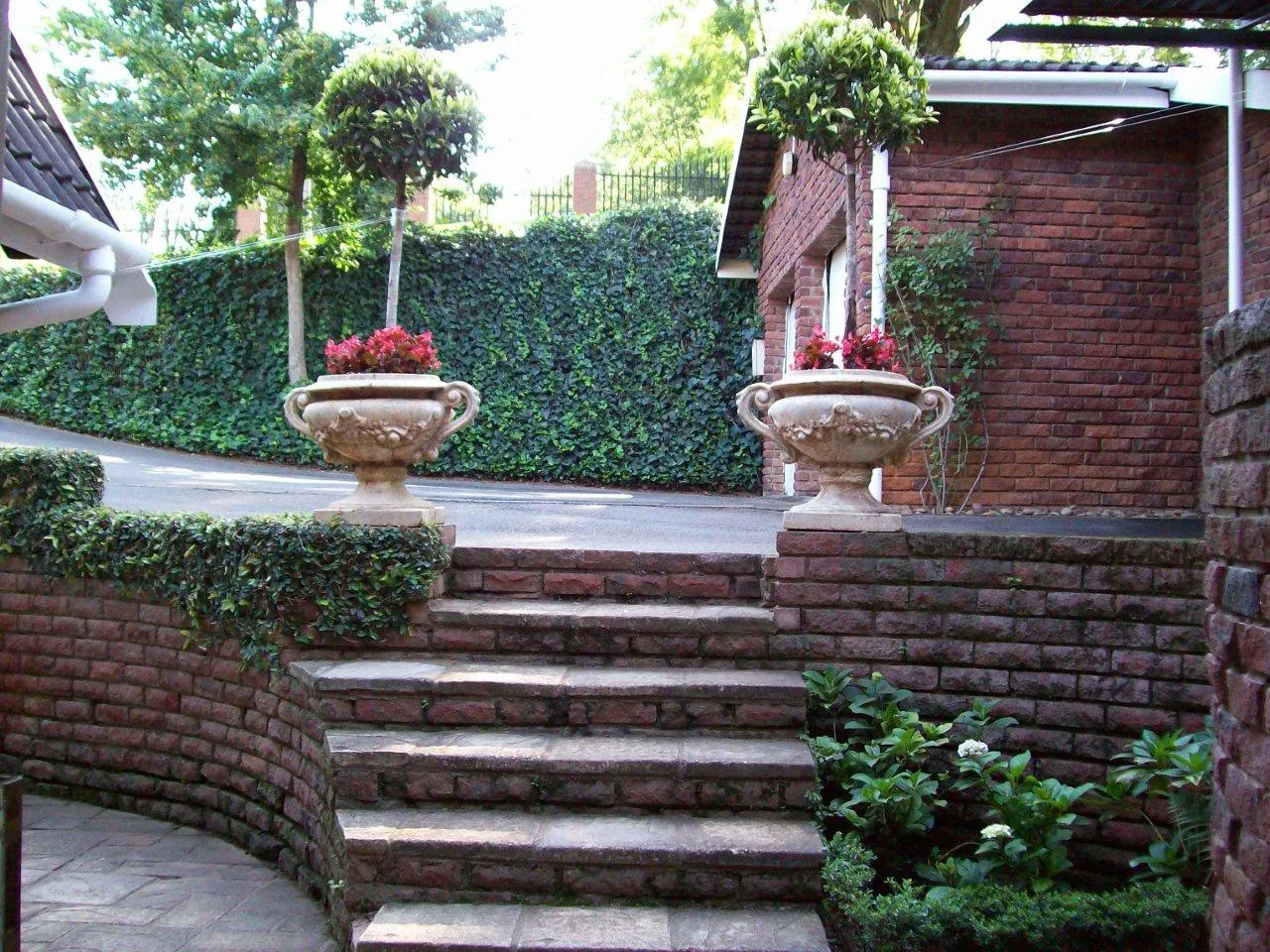 Brick steps with large decorative urns and greenery in a garden setting