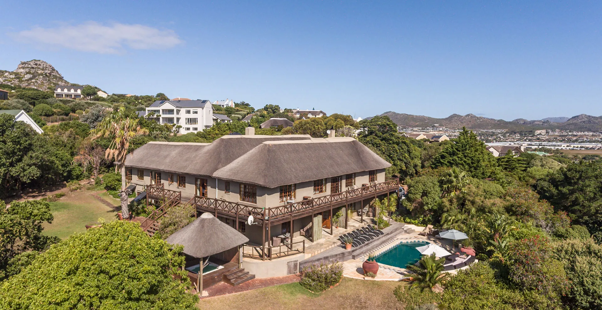 Large house with thatched roof pool and mountain view in a lush area