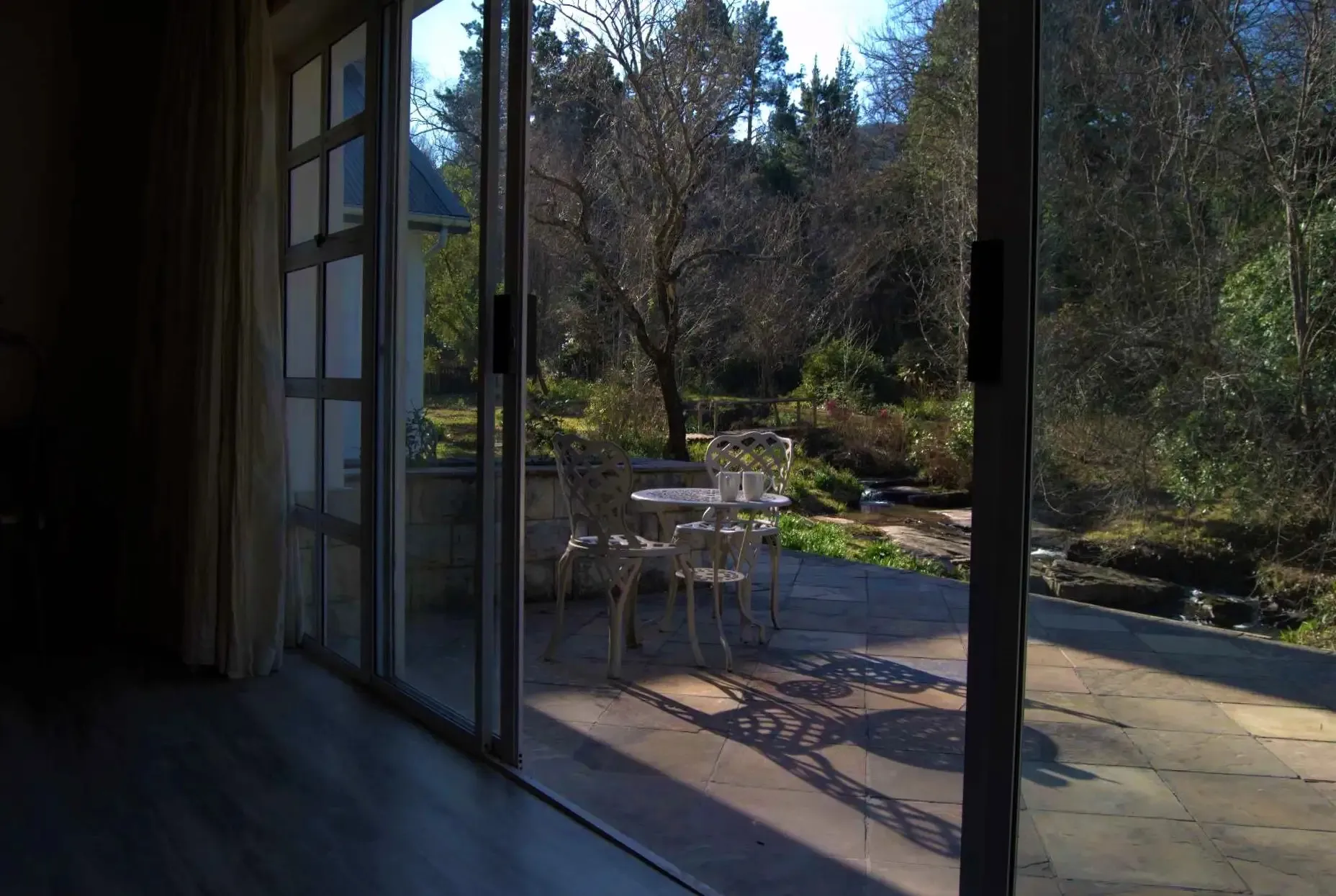 Sliding glass doors open to a patio with chairs and a garden view