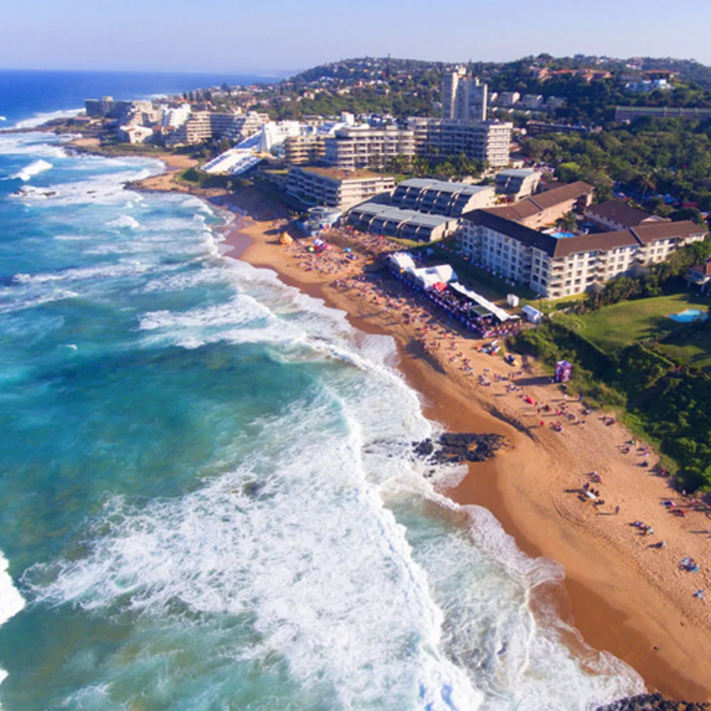Aerial view of a beach with buildings and waves along the shore
